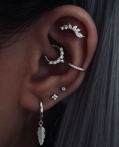 a woman wearing three different ear piercings with leaves and flowers on the side of her ear