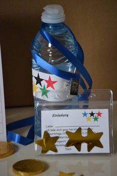 a bottle of water next to some gold stars and a blue ribbon with a name tag on it