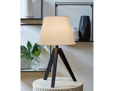 a table lamp sitting on top of a wooden stand next to a mirror and potted plant