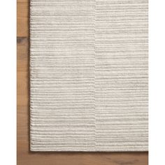 the textured rug is laid on top of a wooden floor, and it's white