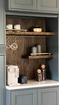 a kitchen with gray cabinets and white counter tops in front of grey cupboards that have wooden shelves above them