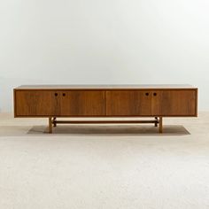 a wooden cabinet sitting on top of a white floor next to a potted plant