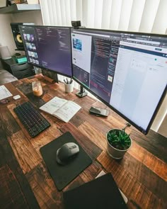 two computer monitors sitting on top of a wooden desk next to a keyboard and mouse