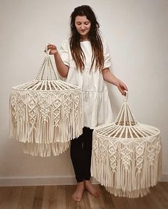 a woman is holding two white macrame lamps