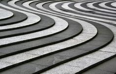 an artistic view of curved stone steps in the shape of spirals on a sidewalk