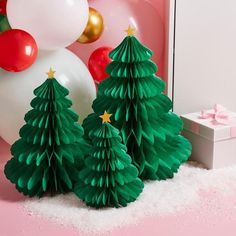 three green paper christmas trees in front of balloons