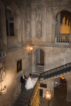 the bride and groom are walking down the stairs at their wedding reception in an old building