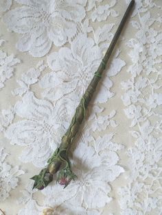 an old fashioned cane is laying on a lace covered tablecloth with flowers and leaves