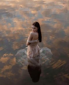 a woman sitting on top of a body of water in the middle of it's reflection