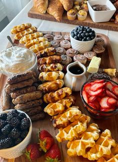 a wooden tray topped with lots of different types of pastries and fruit on top of it