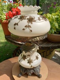 a white vase sitting on top of a wooden table next to potted planters