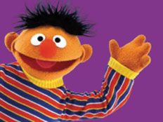 the sesame character is waving his arms in front of an orange and blue striped shirt