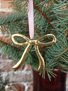 a gold bow ornament hanging from a christmas tree