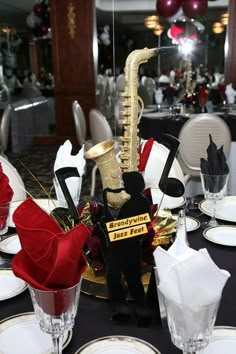 a table set with black and white tables cloths, silverware and red roses