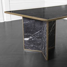 a black marble table with gold trim around the edges and an open door in the background