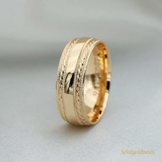 a gold wedding band with engraved details on it