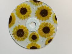 a cd with sunflowers painted on the disc is sitting on a white surface