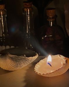 a candle sitting on top of a wooden table next to bottles and seashells