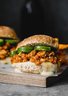 two sloppy joe sandwiches sitting on top of a cutting board