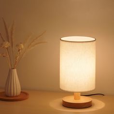 a table lamp sitting next to a vase with flowers in it on top of a table