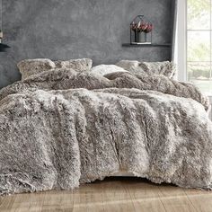 a bed covered in grey fur next to a window