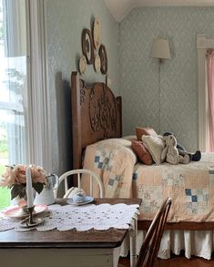 a bed room with a neatly made bed next to a table and two chairs in front of a window