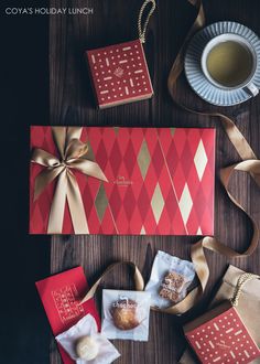 a table topped with red and gold wrapped presents next to a cup of coffee or tea