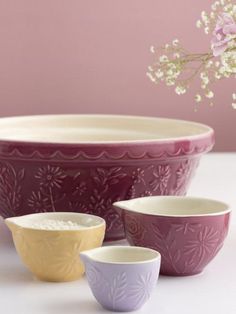 three bowls are sitting on a table with flowers in the background