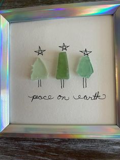 three small trees are in a frame with the words peace on earth written below them