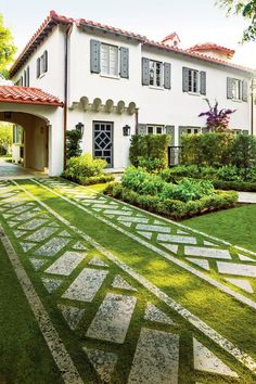 a large white house sitting on top of a lush green field next to a garden