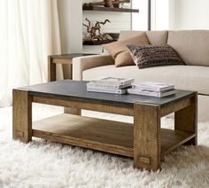 a coffee table sitting on top of a white rug in front of a beige couch