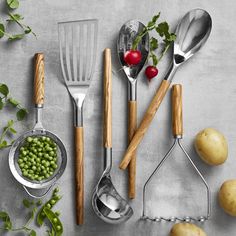 various kitchen utensils and vegetables on a gray surface with green beans, radishes, peas, potatoes