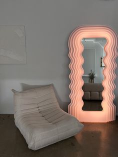 a chair and mirror in a room with a large light on the wall behind it