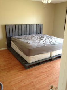 a bed frame made out of pallets in a room with hardwood floors and walls