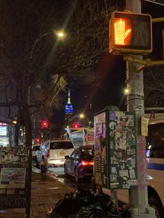 a city street at night with cars parked on the side of the road and traffic lights in the background