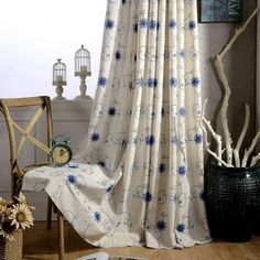 a chair and table in front of a curtain with blue flowers on the drapes