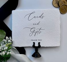 a white card with the words cards and gifts written on it next to some flowers