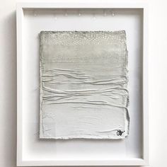 an abstract painting in a white frame on the wall