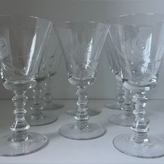 four wine glasses are lined up on a table