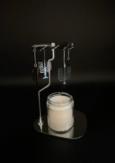 a candle with candlesticks on it sitting next to a glass container filled with liquid