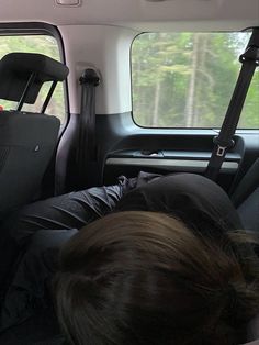 a man sleeping in the back seat of a van with luggage on it's back