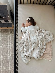 a small child laying in a crib with a blanket on it's back