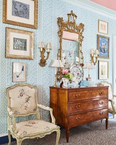 a dresser and chair in a room with pictures on the wall