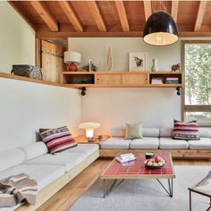 a living room filled with lots of furniture next to a wooden ceiling mounted book shelf