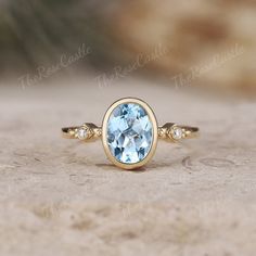 an oval blue topazte ring with two diamonds on the sides, set in yellow gold