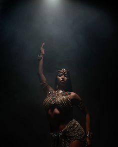 a woman in a belly dance costume is holding her hand up