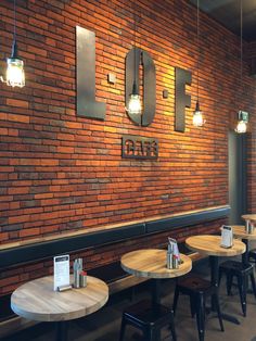 the interior of a restaurant with brick walls and wooden tables, lamps hanging from the ceiling