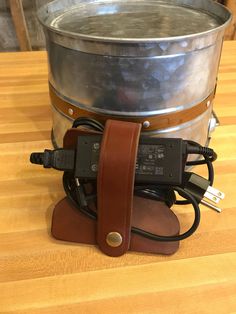 a large metal bucket sitting on top of a wooden table next to a charger