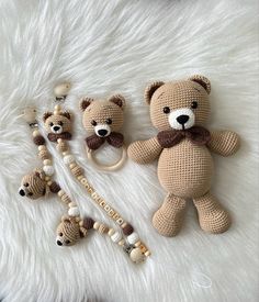 three crocheted teddy bears and two pacifiers on a white fur surface