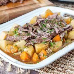 a white plate topped with meat and potatoes on top of a table next to a cutting board